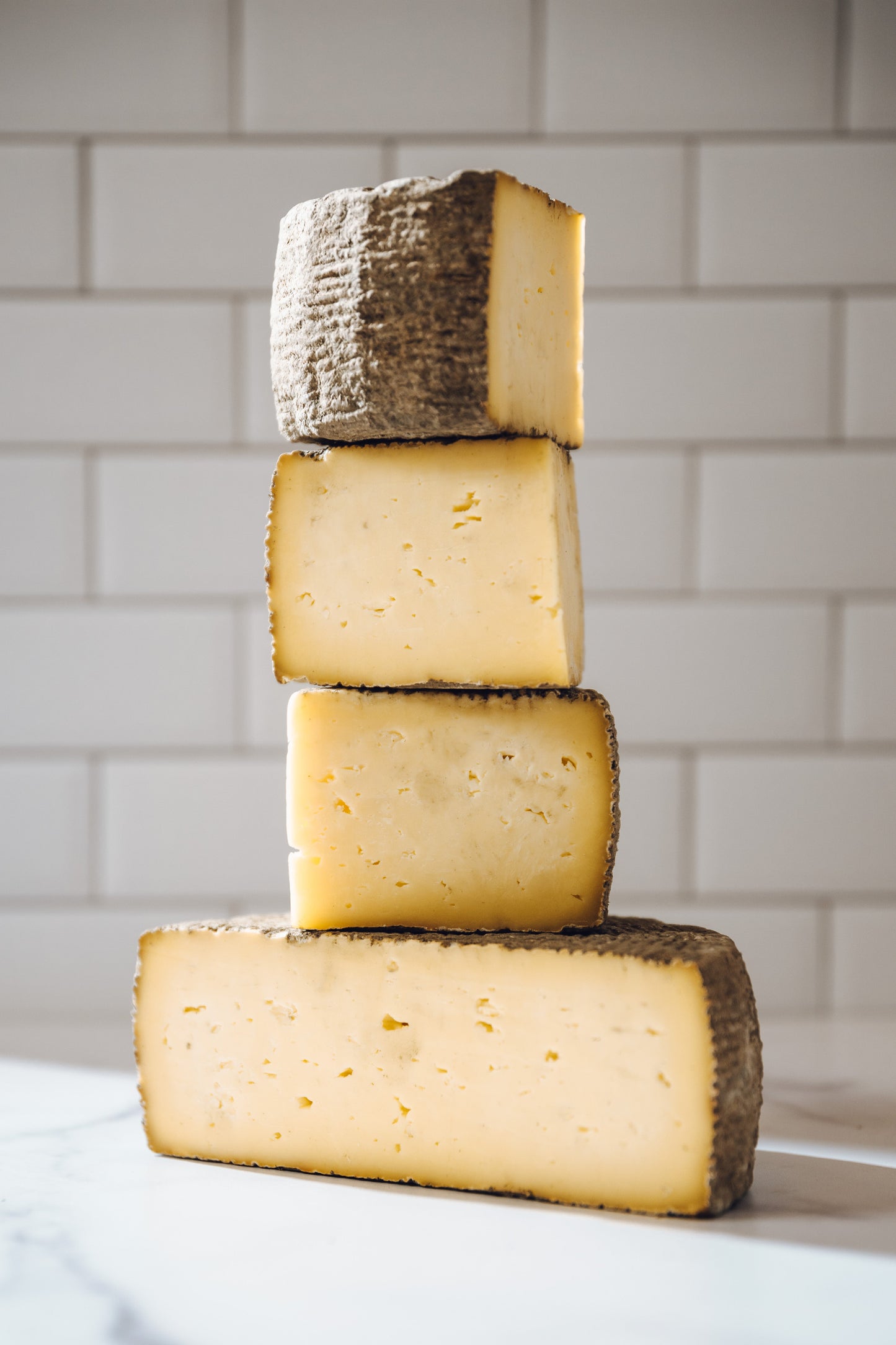 8oz Swallow Tail Tomme Cheese Wedge stacked
